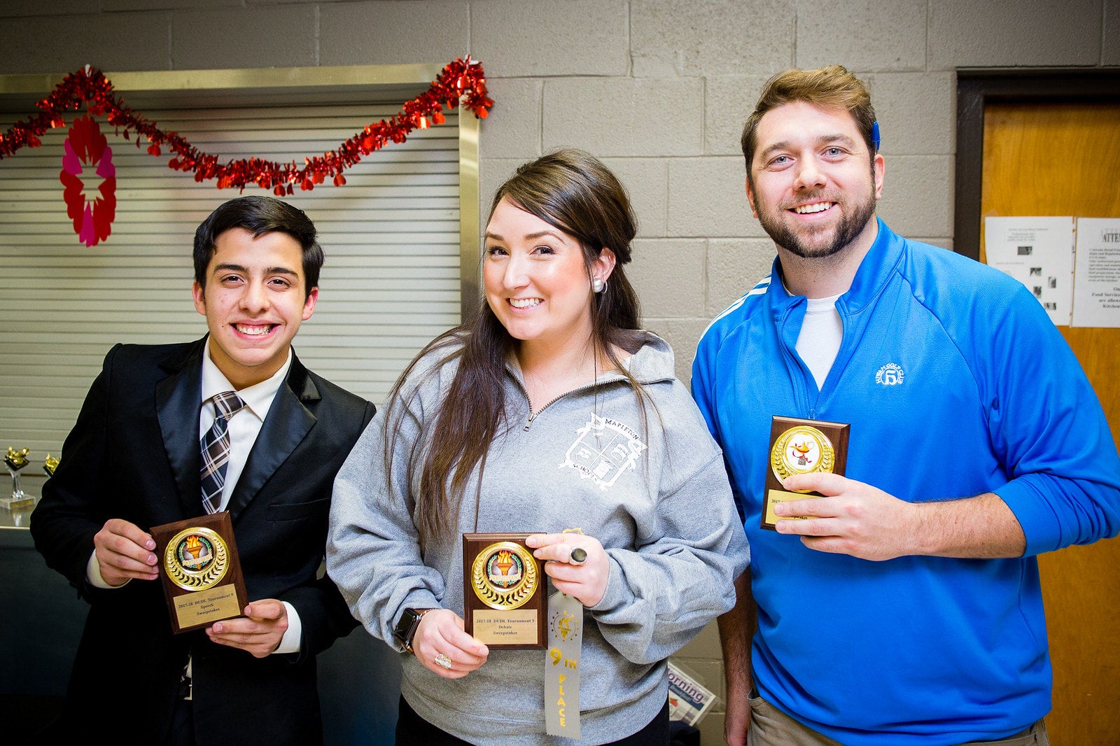 three people holding awards